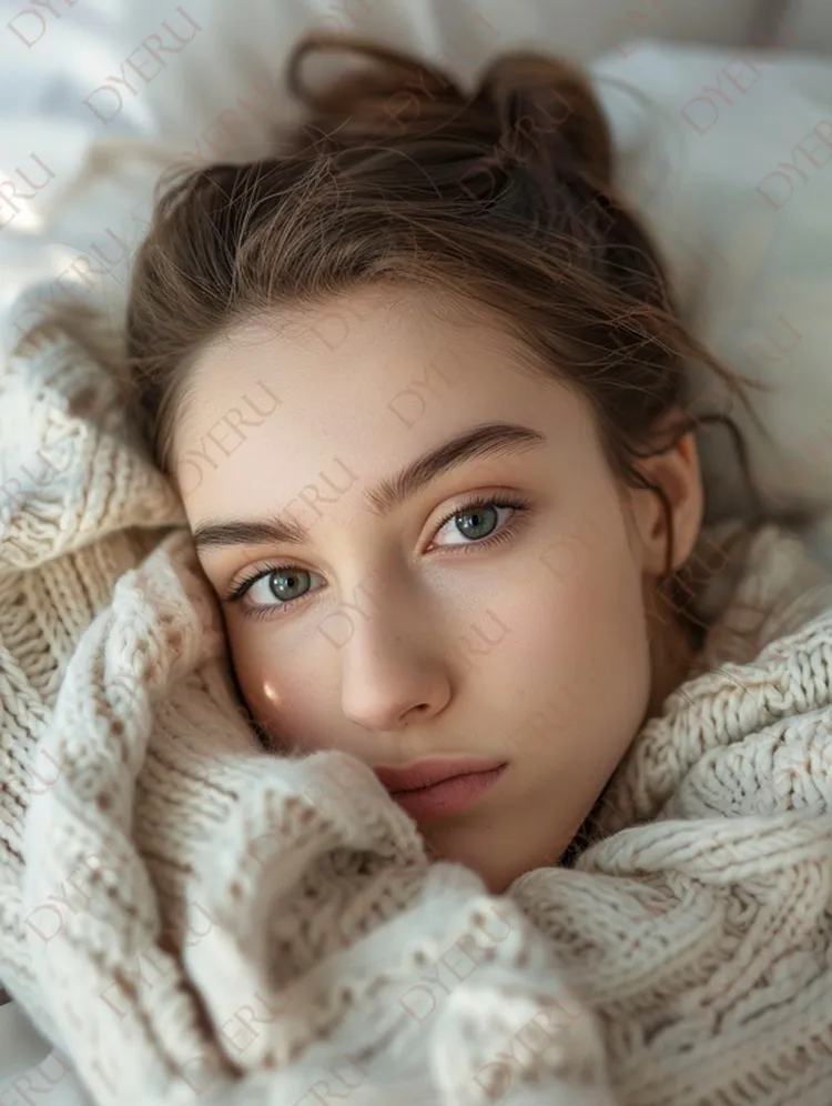 สาวสาวสวยในผ้าพันคอถักนิตสีครีมที่นอนอยู่บนเตียง